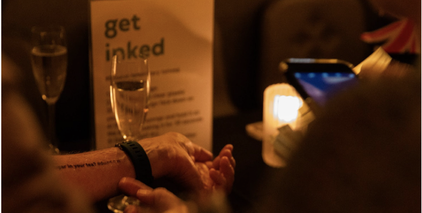 Table at a bar with temporary tattoos and a get inked sign