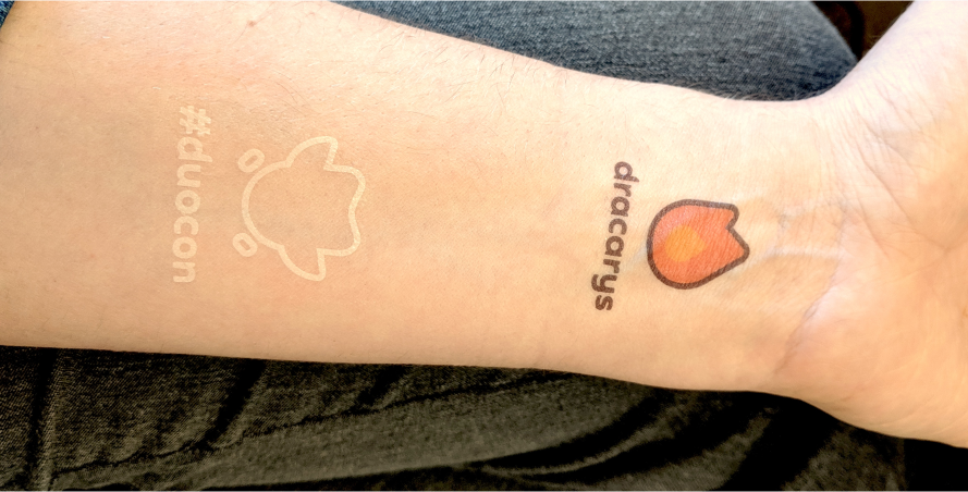 Forearm with a Duocon logo tattoo and a dracarys streak flame